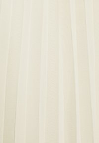 Tessuto di crema chiaro con righe verticali e una sottile trama. Il materiale appare morbido e leggermente traslucido, permettendo alla luce di filtrare.