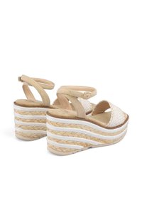 Sandalias de cuña beige con un empeine de tejido trenzado y múltiples capas de yute trenzado. Presentan una correa en el tobillo por la parte posterior y un diseño de punta abierta.