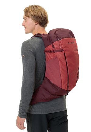 Zaino rosso e bordeaux con tessuto testurizzato, spallacci regolabili e tasche esterne; presenta il logo del marchio sul lato.