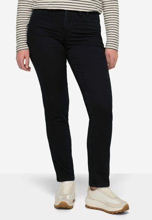 Donkerblauwe, slim-fit jeans van denim, met voorzakken en ritssluiting, gecombineerd met lichtgekleurde sneakers en een gestreepte lange mouwen shirt.