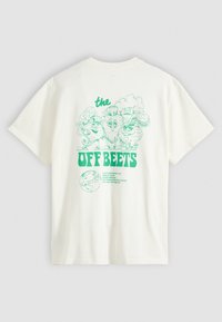T-shirt blanche avec des légumes cartoon verts portant des lunettes de soleil au-dessus du texte "the OFF BEETS" et un petit graphique de globe.