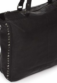 Zwarte leren tote bag met zilveren studaccenten aan één zijde, ritssluiting en dubbele handvatten voor eenvoudig dragen.