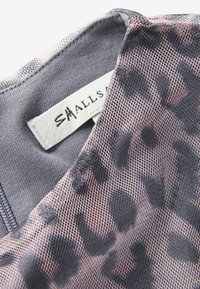 Průhledný síťovaný top šedé barvy s růžovým leopardím vzorem. Obsahuje štítek s názvem značky "SMALLS" poblíž výstřihu.