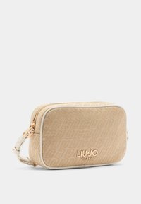 Beżowa torebka na ramię z wzorem, z złotymi elementami, zamykana na zamek błyskawiczny i z wytłoczonym logo. Gładka tekstura z kontrastującą białą lamówką.