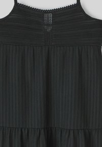 Robe noire avec texture ribbed verticale, fines bretelles réglables et garniture en dentelle au niveau du décolleté. Comprend une taille froncée.