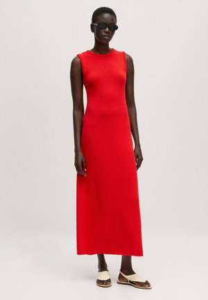 Rotes gestricktes Maxikleid mit rundem Ausschnitt und strukturiertem Stoff. Getragen mit hellen Sandalen und dunklen Sonnenbrillen.