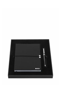 Cahier noir de la marque BOSS avec élastique et stylo assorti, présenté dans une boîte cadeau noire avec insert en mousse.