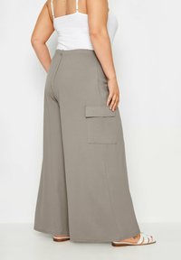 Breda cargo byxor i ljusgrå, tillverkade av mjuk bomull. Har en sidoficka och elastisk midja. Slät textur och lös passform.