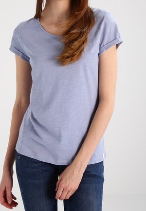 T-shirt à manches courtes violet clair avec un col rond, une texture douce et des revers roulés, associé à un jean en denim bleu foncé.