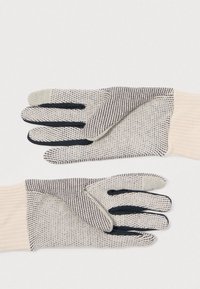 Beige spalvos megzti pirštinės su tamsiomis juostelėmis, turinčios juodus pirštų galus ir darinį su grioveliais. Minkšta tekstūra su funkcionaliu dizainu.