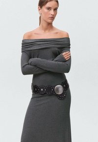 Šedé šaty bez ramienok s dlhými rukávmi, priliehavý strih a široký čierny opasok s kruhovými akcentmi a kovovou prackou.