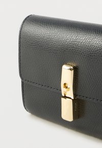 Sort tekstureret læderpung med lukning i guld. Har en glat finish, kompakt design og fine syningsdetaljer.