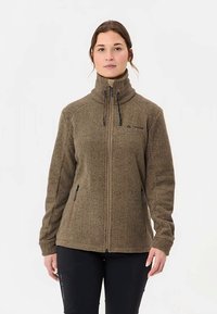 Bruine fleecejas met een hoge kraag, ritssluiting en twee zijzakken. Heeft contrasterende stiksels en een klein logo op de borst.