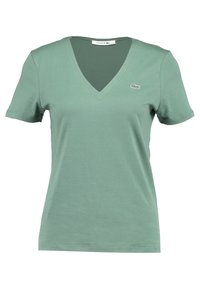 Grön bomullströja med v-ringning, korta ärmar och en liten broderad logo på vänster bröst. Mjuk tygkvalitet och avslappnad passform.