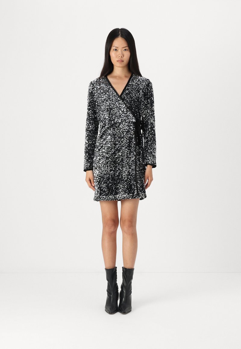 Μαυρένιο παλτό φόρεμα με παγιέτες, μακριά μανίκια και ζώνη στη μέση. Έχει υφή και κοντή γραμμή. Φορεμένο με μαύρες μποτάκια μέχρι τον αστράγαλο.