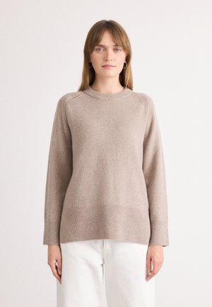 Pull en tricot beige avec un col rond, des manches longues, un ourlet côtelé et des détails de couture décoratifs aux épaules. Texture lisse.