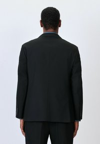 Schwarze Anzugjacke mit taillierter Passform, versehen mit einem Reverskragen, langen Ärmeln und einer glatten Textur. Keine sichtbaren Verzierungen oder Muster.