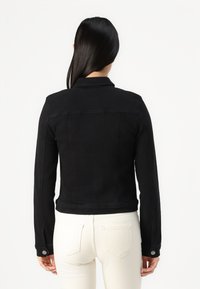 Svart denimjakke med en tettsittende design, knappelommer og cropped lengde. Har en klassisk krage og bakgrop detaljer.