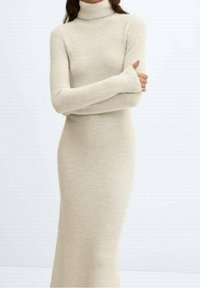 Robe beige à col roulé avec manches longues, confectionnée en tissu maille douce ; coupe ajustée s'étendant jusqu'aux chevilles, avec texture côtelée.