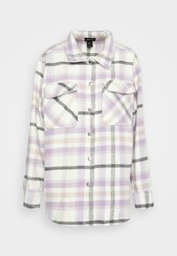 Oversized flanellen shirt in wit, lavendel en beige ruitjes. Heeft twee borstzakken, een knoopsluiting en een ronde kraag. Zachte textuur.