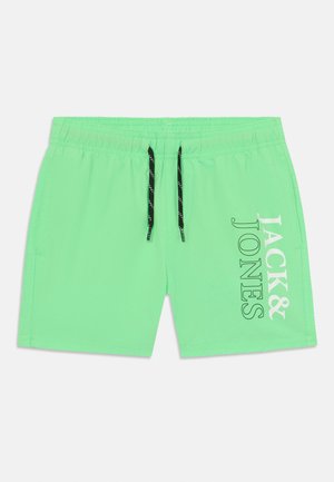 Green swim shorts made of lightweight fabric. Features a black drawstring and white printed text "JACK & JONES" on the side.