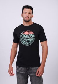 Zwarte katoenen t-shirt met een ronde graphic van golven, bergen en een opkomende zon in aqua en koraalkleuren. Korte mouwen, ronde hals.