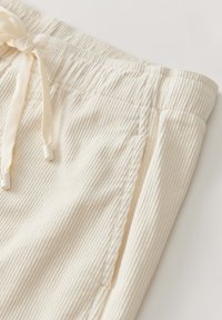 Crème-kleurige, geribbelde stofshorts met een elastische taille band en een trekkoordsluiting. Voorzien van zijzakken en een zachte textuur.