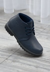 Blå lær ankle boot med en glat overflade, rund tå, sort gummisål og blå snørebånd. Har subtile branding på siden.