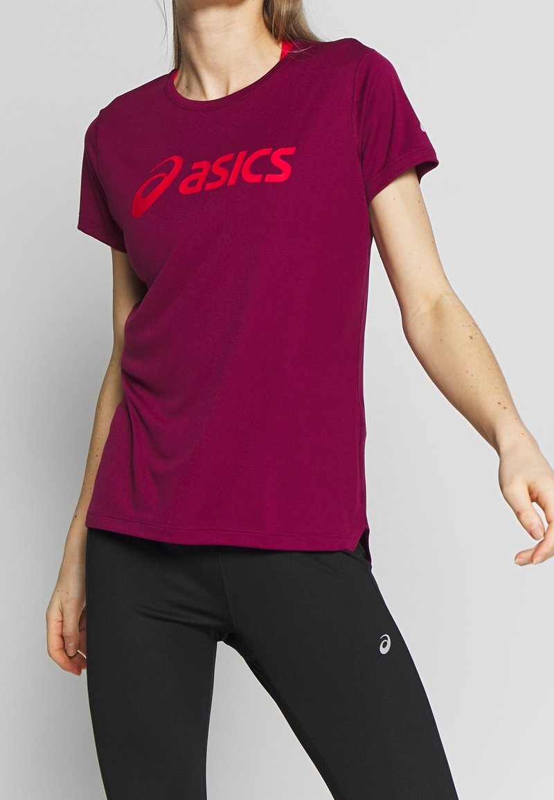 Camiseta deportiva burdeos en tejido ligero con un gran logotipo rojo de "asics". Manga corta y escote redondo con aberturas laterales.