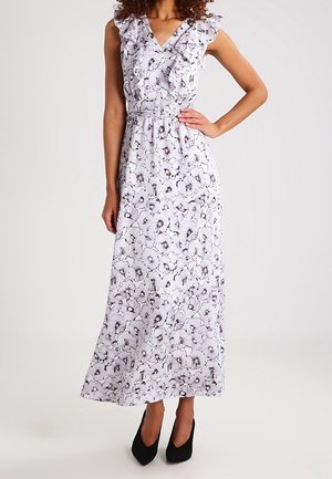 Bílé bezrukávové maxišaty s černým květinovým vzorem, volánkový véčkový výstřih, zvýrazněný pas, nošeno s černými lodičkami s špičatou špičkou.