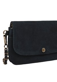 Pochette en daim bleu marine avec fermeture à rabat, quincaillerie dorée et bandoulière chaîne amovible. Présente une texture lisse et des lignes épurées.