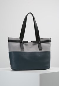 Borsa tote in pelle bicolore grigia e blu scuro con manici neri, posizionata su una piattaforma bianca contro uno sfondo semplice.