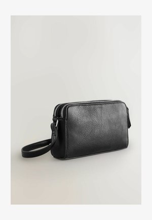 Melna ādas rokassomiņa ar strukturētu apdari, divām sudraba rāvējslēdzēm un atbilstošu plaukstas siksnu. Kompактa taisnstūra forma.