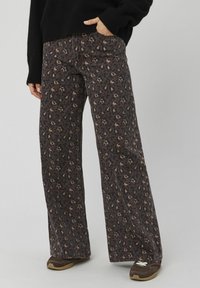 Pantalon à jambes larges imprimé léopard en marron foncé et beige, fabriqué en tissu texturé. Il présente une taille haute et des poches latérales pratiques.