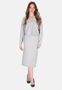 Grijze gebreide cardigan met een v-hals en knoopsluiting, gecombineerd met een bijpassende pencil skirt, met een gladde textuur en een aansluitende pasvorm.