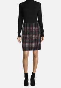 Svart polotröja kombinerad med en åtsittande kjol med ett rutmönster i svart, grått och burgundy. Mjuk tyg och knälång design.