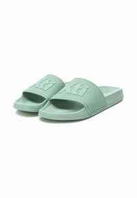 Sandalias de goma verde con una tira texturizada que presenta el logo "Xti". Suela plana y diseño de punta abierta para un uso fácil.