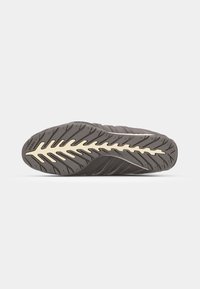 Athletic shoe with a textured dark grey upper, featuring accenting stripes, and a flexible rubber sole with a leaf-like tread pattern.