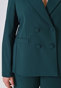 Teal dubbelzijdig blazer van gladde stof met grote ronde knopen, reverskraag en zijzakdetail.