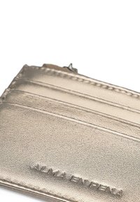 Metalen gouden kaarthouder met een textuur oppervlak, voorzien van vier kaartsleuven en een ritscompartiment. Geëmbosseerd merk op de voorkant.