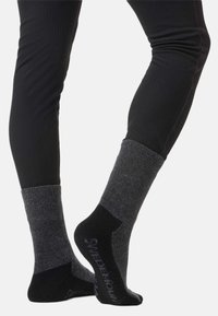 Ciemnoszare i czarne skarpetki o prążkowanej fakturze, z wzmocnionym palcem i piętą, z logo na podeszwie. Elastyczne i zaprojektowane z myślą o komforcie.