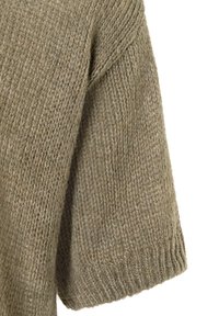 Naheaufnahme eines weichen, dicken, gestrickten beigen Pulloverbunds mit einem gerippten Bündchen und strukturiertem Garnmuster.