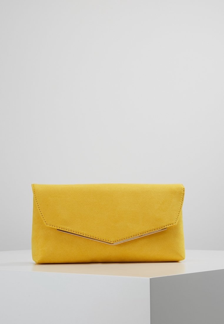 Pochette enveloppe en suède jaune avec rabat incliné et couture subtile, posée sur une surface géométrique blanche sur fond uni.