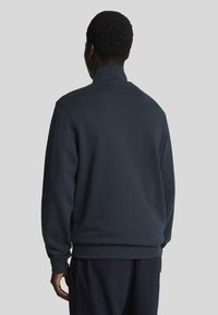 Donkerblauwe sweatshirt met een hoge kraag, lange mouwen en een relaxte pasvorm. Glad materiaal, zonder zichtbare patronen of accenten.