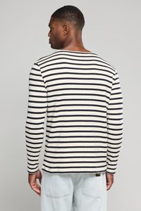 Gestreiftes Langarmhemd in Creme und Marineblau. Verfügt über einen Rundhalsausschnitt und einen weichen Stoff mit lockerer Passform. Die Rückansicht zeigt Nahtdetails.