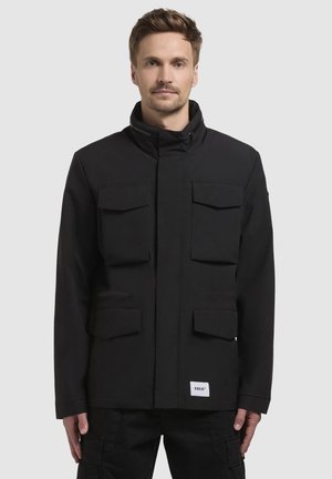 Giacca utility nera con colletto alto, quattro tasche anteriori, chiusura a zip e etichetta con logo sull'orlo, realizzata in tessuto resistente.