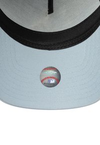 Baseball cap with a light blue fabric crown, black brim, and a round MLB label on the underside featuring red stitching and silver accents.