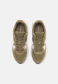 Olivegrønne sneakers med ruskind- og stofpaneler, hvide detaljer, runde snørebånd og en tekstureret indersål. Har guld detaljer og branding.