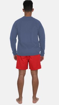 Blå långärmad skjorta med rund halsringning, i kombination med röda badshorts. Tyget verkar smidigt och har en avslappnad passform.