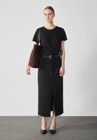 Black short-sleeve t-shirt paired with a knee-length black denim skirt featuring a front slit and frayed hem, accessorized with a brown tote bag and black pointed heels.